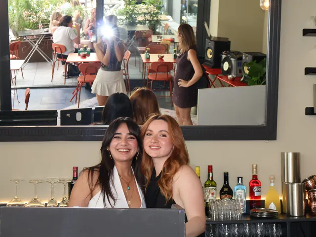 Günay and Nemo smiling behind the bar